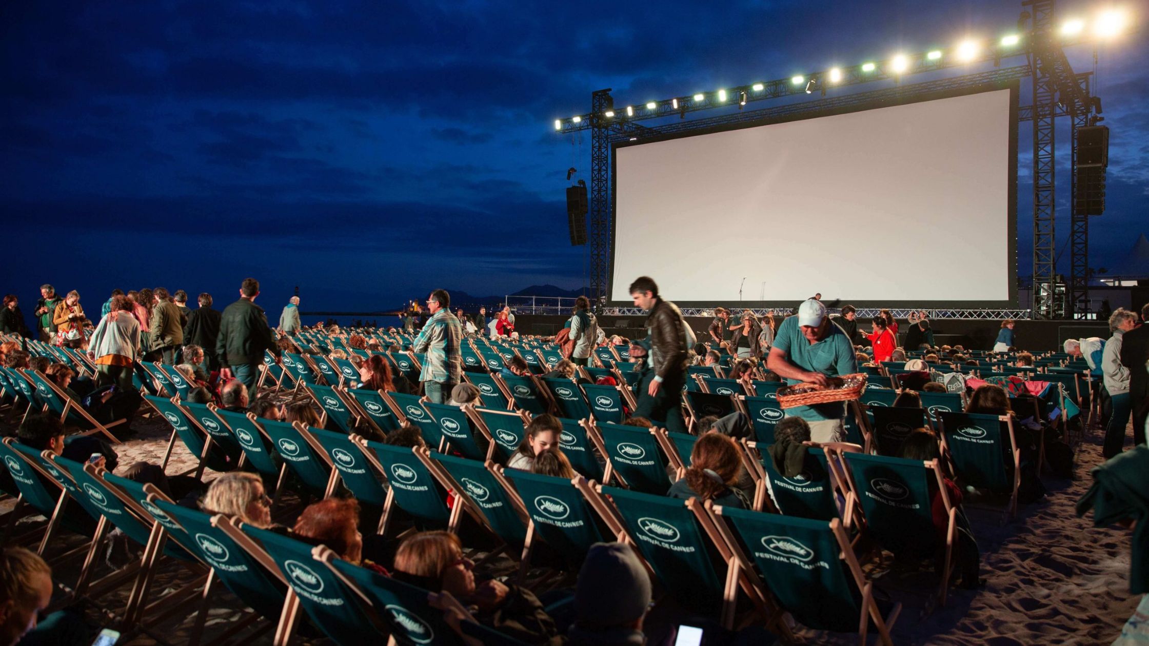 How do outdoor movie screens differ from indoor movie screens?